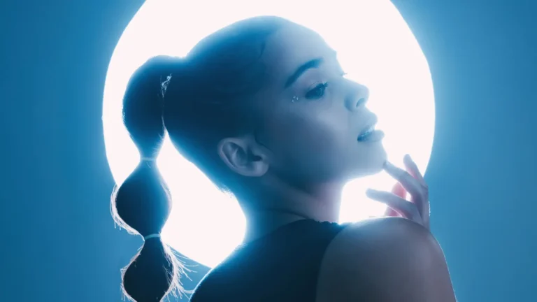 Elegant young woman standing against a radiant aura with soft blue light shining around her, creating a mystical and serene atmosphere