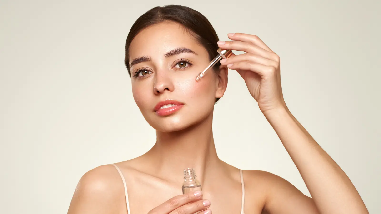 A beautiful young woman with flawless glowing skin applying skincare cream to her face in natural light, promoting healthy beauty and self-care.